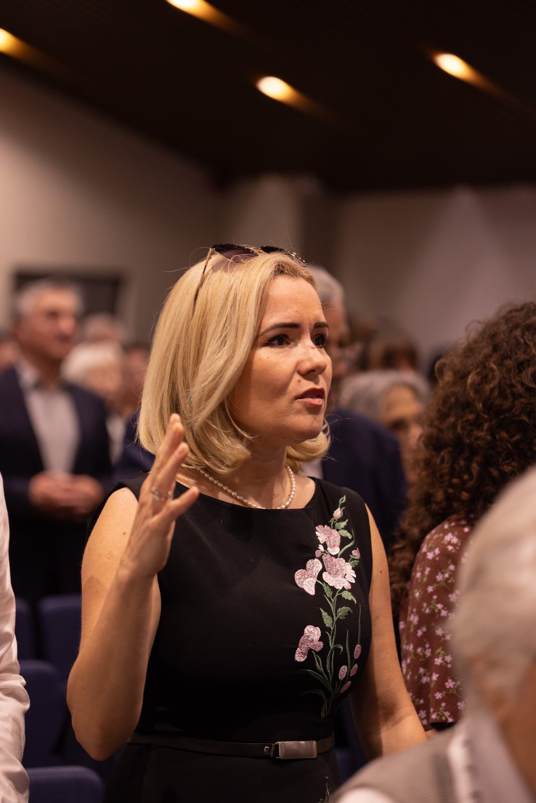 O soră cu mâna ridicată în închinare, în picioare între rânduri